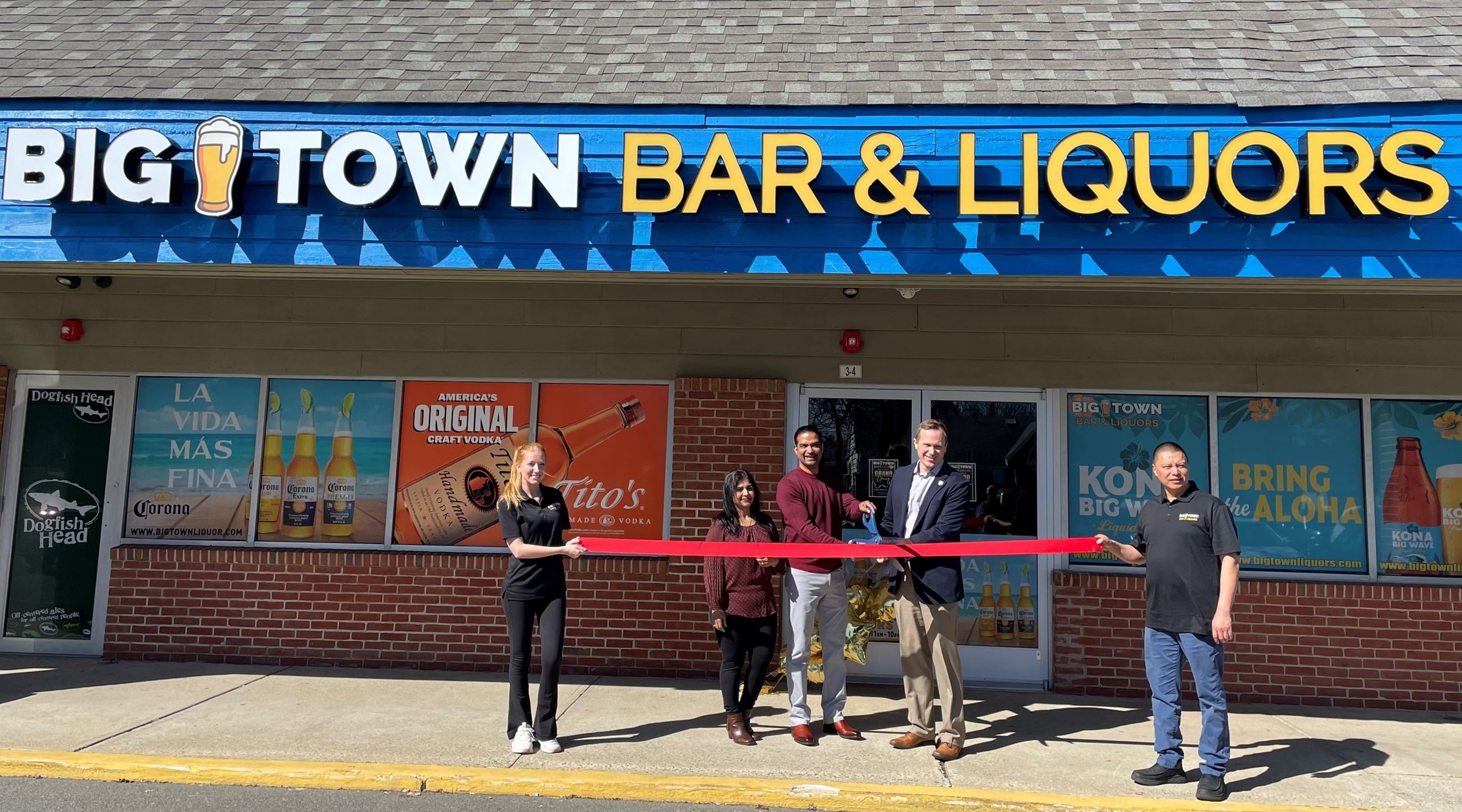 Mayor and Owners standing out front of business with ribbon and scissors