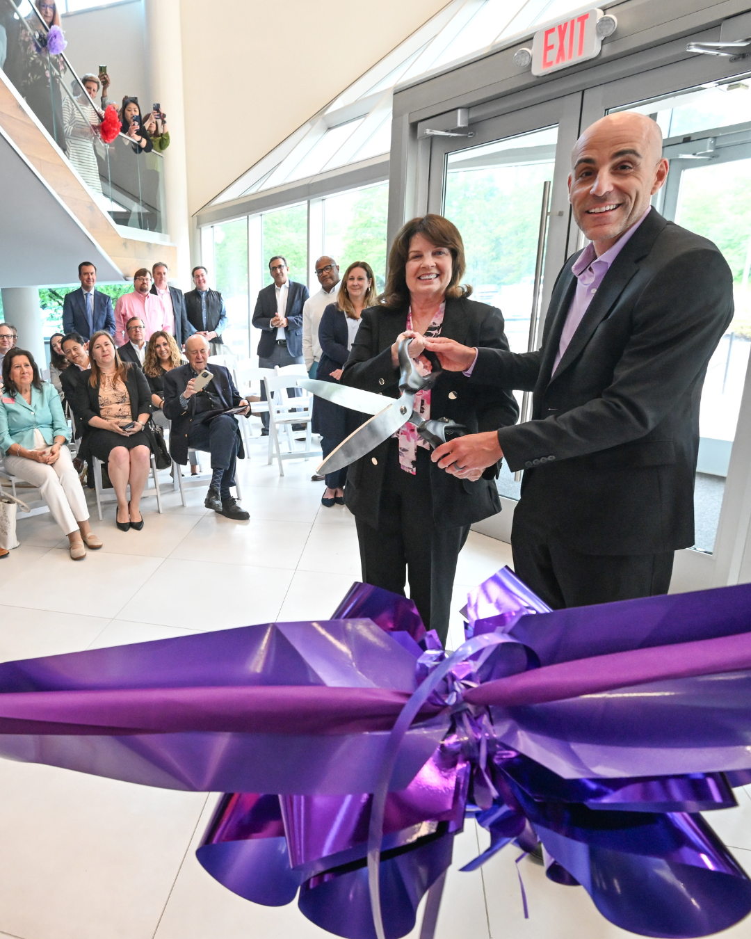 Regina (Founder) and Anthony (Councilman of Hamilton Township) holding scissors near purple ribbon